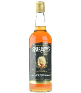 Sparrow's Premium Old Rum bottle standing on a rustic wooden table with a blurred distillery background