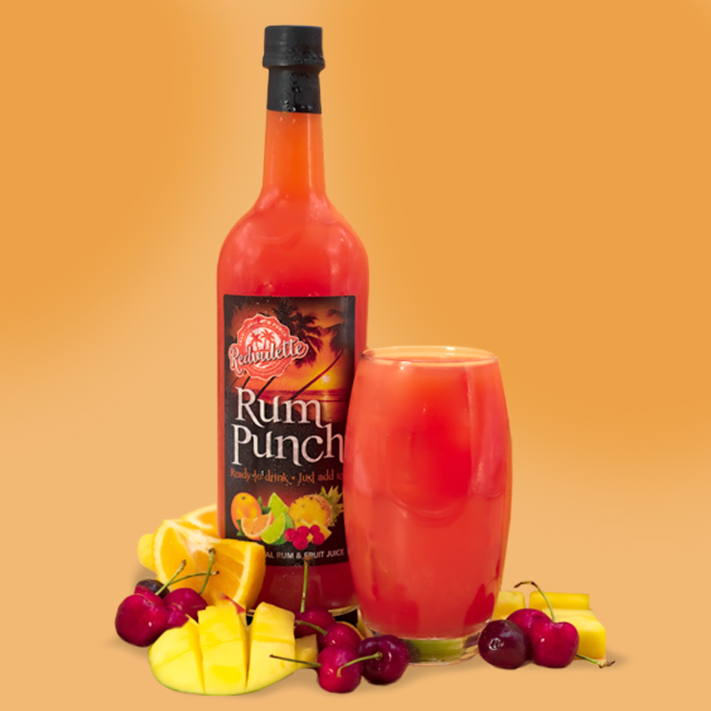 Sunset Rum Punch bottle surrounded by tropical fruits and spices on a rustic wooden surface