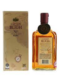 Sunset Captain Bligh XO rum bottle with clear glass and aged barrels in background