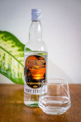 Sunset Very Strong Rum bottle surrounded by spices and wooden elements on a dark background