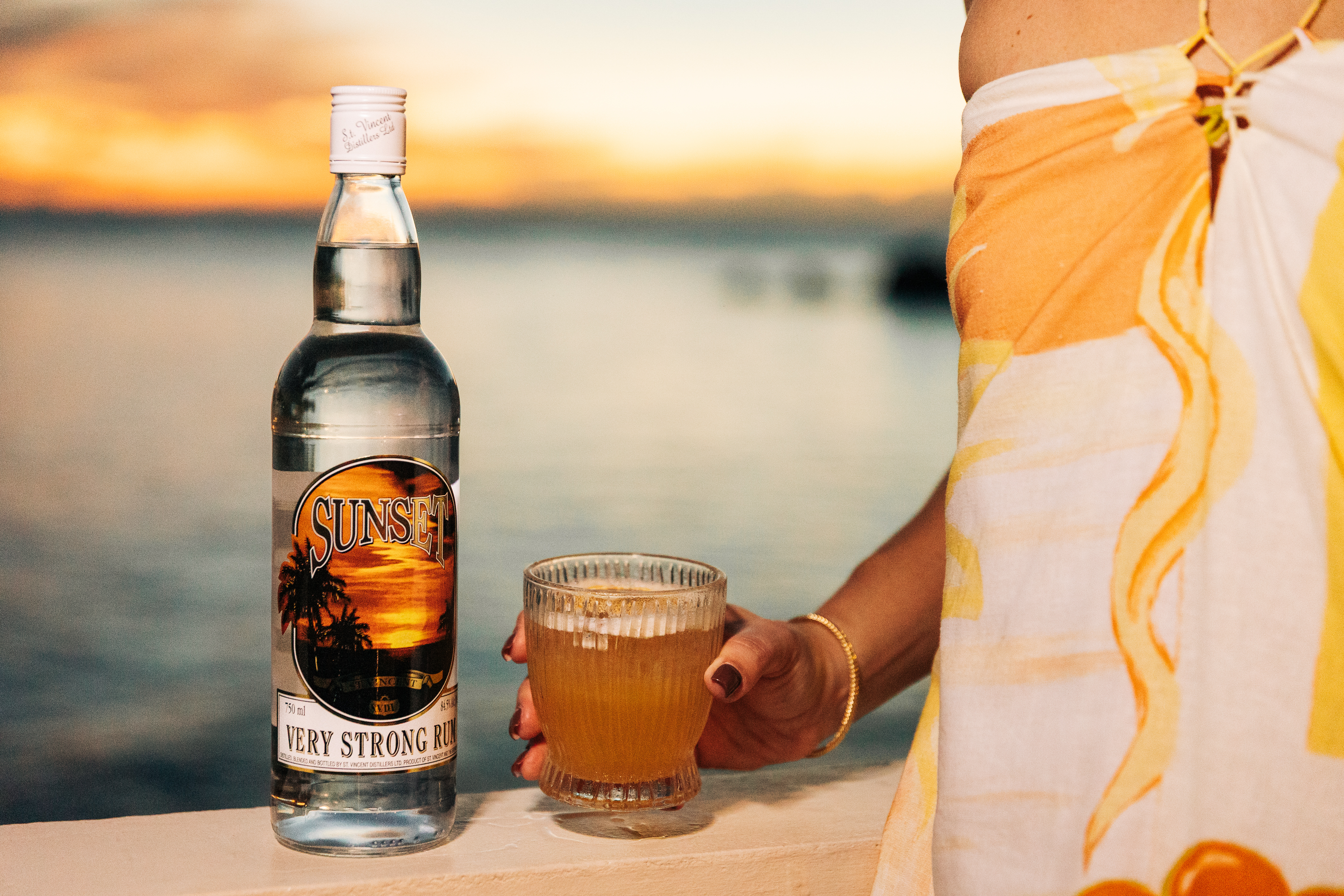 Sunset Very Strong Rum bottle surrounded by spices and wooden elements on a dark background